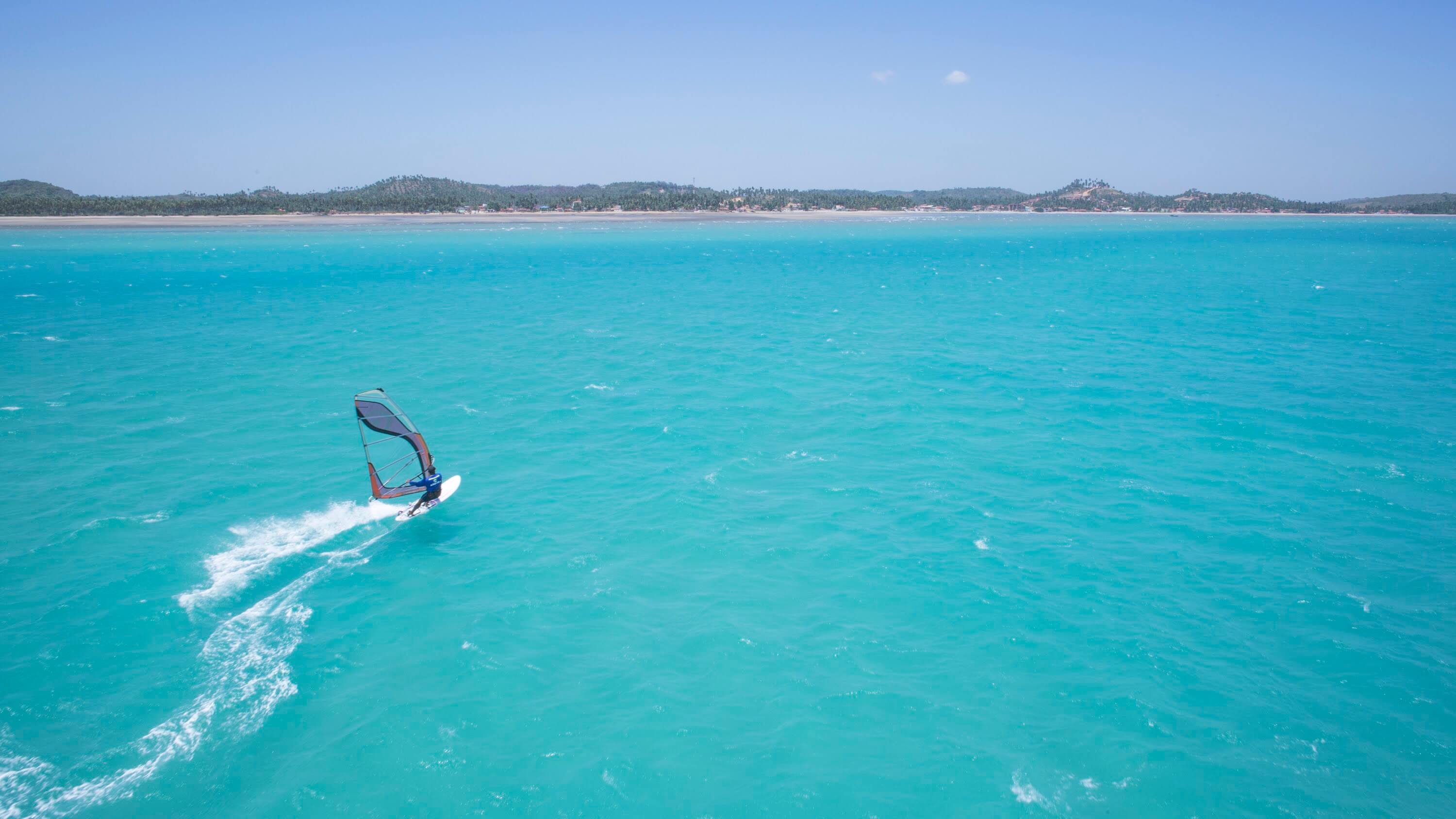 Homem praticando Windsurf em prancha com vela no mar da Croa de São Bento.